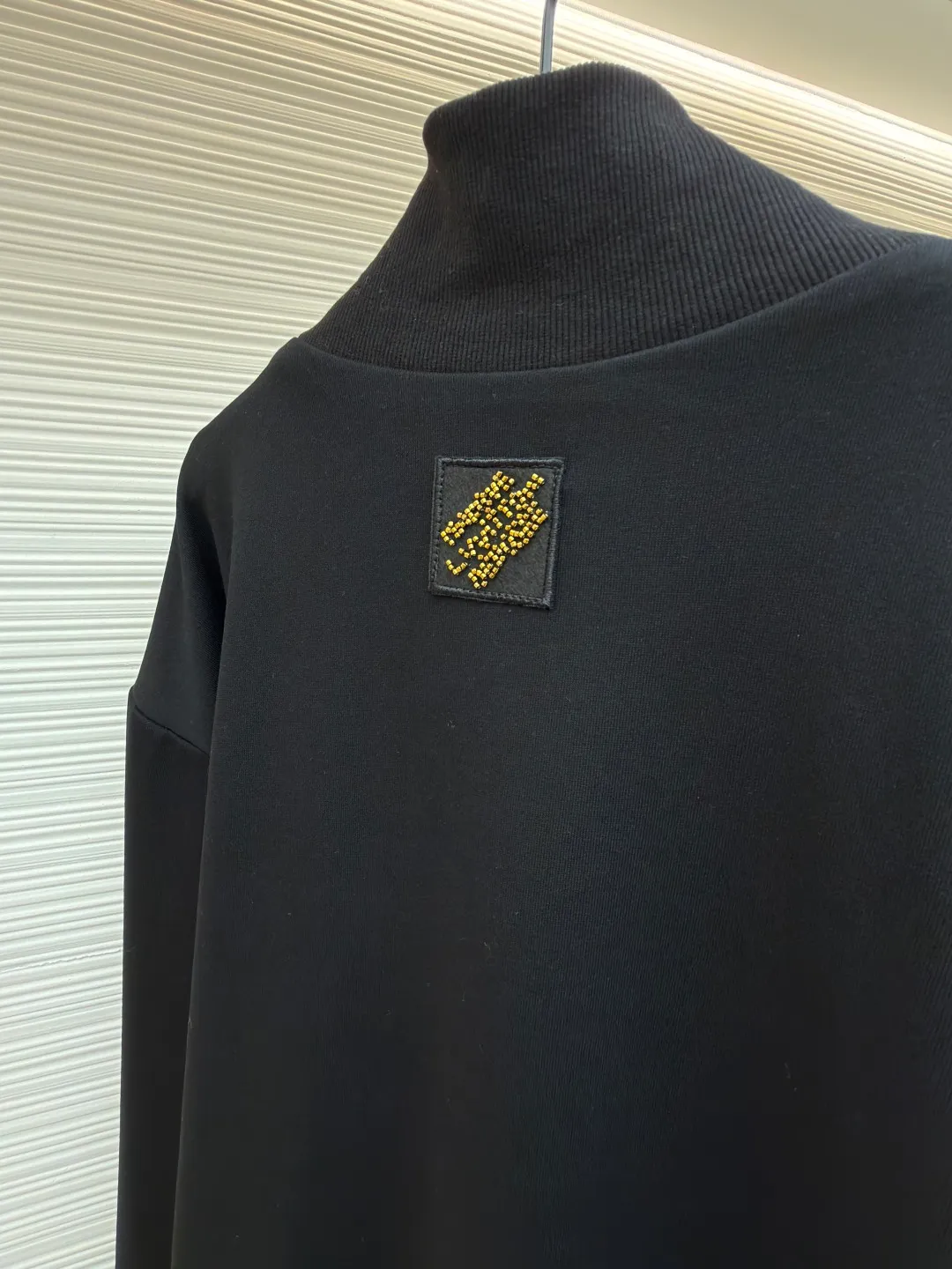 LOUIS VUITTON stand-up collar ribbed hem long-sleeved logo decorated jacket ●Original version: Purchased and developed at 25899 ●Item number: 1682404-B25 ●Fabric: cotton fabric ●Technology: knitted production ●Color: black ●Version: fitted version ●Weight: about 990 grams ●Size: S-M-L-XL ●Description: This Louis Vuitton stand-collar zipper jacket is made of high-thread-count cotton-elastic blended fabric, which has been treated with enzyme washing process. The fabric is soft to the touch and has good wrinkle resistance and elasticity. The body has a delicate matte texture. The LV logo on the chest uses a combination of gold thread embroidery and patchwork. The embroidery uses interlaced flat stitch and chain stitch techniques. The stitch density reaches 12 stitches per centimeter. The edges are overlocked and the pattern is three-dimensional and not easy to fall off. The jacket adopts a stand-up collar design, and the collar ribs are made of spandex blended material, which has been shaped to ensure that it will not loosen after long-term wear. The front is equipped with a custom brass zipper, and the zipper teeth are polished and gold-plated, making it smooth, wear-resistant and of high-quality texture. The side seam pockets are welted, and the seams are reinforced with double-needle sewing. The ribbed edges of the cuffs and hem are woven with high-elastic yarns of the same color. The shoulders are seamlessly spliced ​​with natural shoulder shapes. The overall craftsmanship combines the brand's classic elements with practical design, fully demonstrating the production level of high-end clothing. The overall wiring is straight and delicate, the fabric is comfortable and soft, and the color is consistent without color difference. It can be matched with the same style to create a fashionable look and control various occasions. Customized accessories, complete with three standards, same style for men and women!
